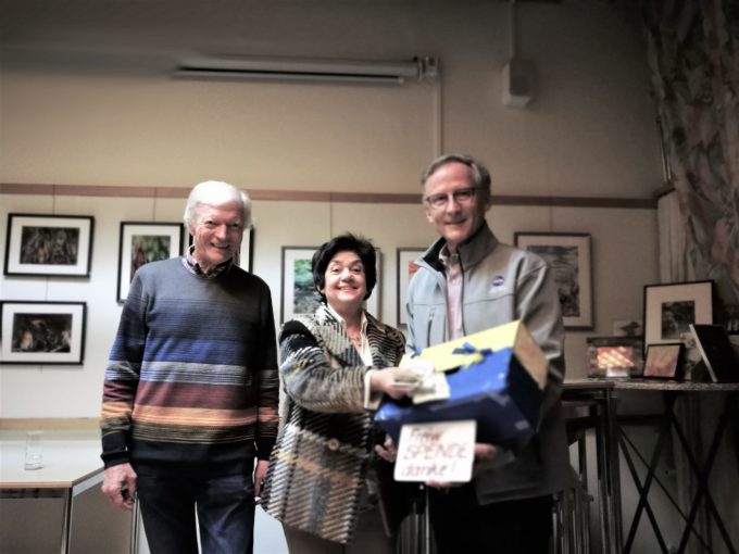 Dame, flankiert von zwei Herren gibt Geld in Schachtel l steckt Geld in Schachtel schamit Herren